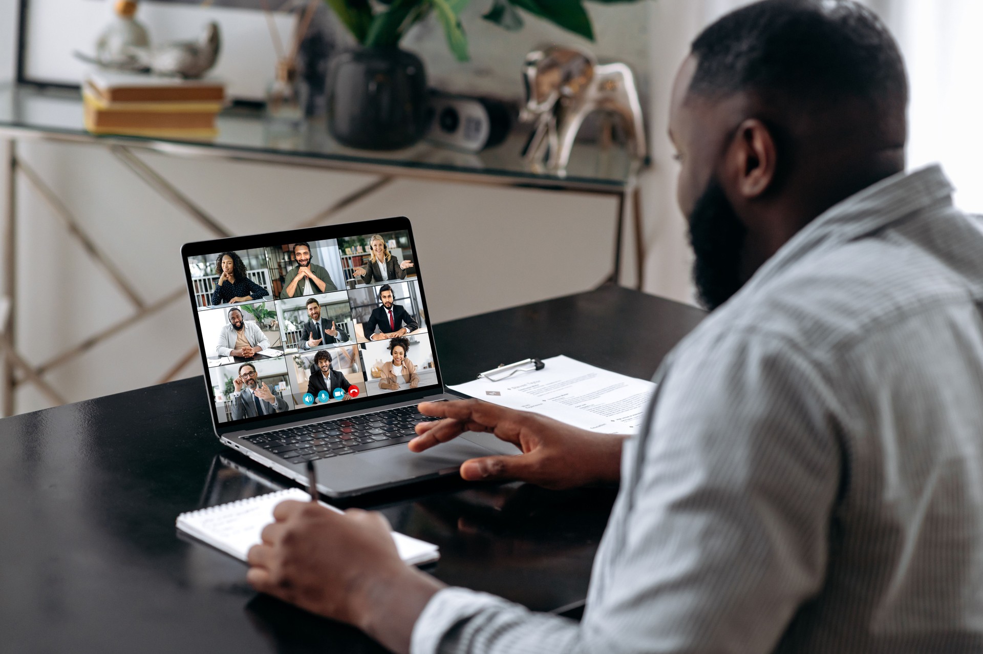 African american man talking with colleagues by video call uses laptop and app, takes notes, discuss ideas. Group brainstorm, online video meeting, virtual conference with multiracial colleagues